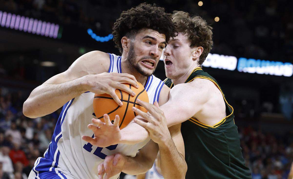 Duke’s Cameron Boozer (12) keeps the ball from Siena’s Riley Mulvey (55) during the second half of Duke’s 71-65 victory over Siena in the first round of the NCAA Men’s Basketball Tournament at  Bon Secours Wellness Arena in Greenville, S.C., Thursday, March 19, 2026.