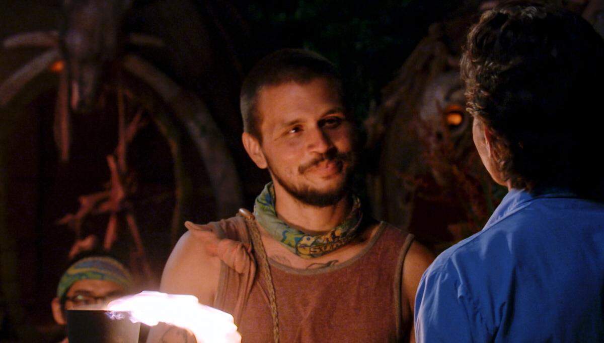 Jesse Lopez wears a dusty red tank top and a green bandanna around his neck. 