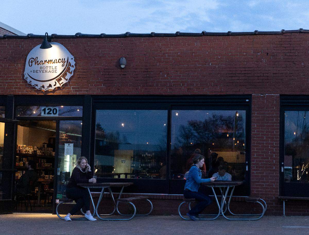 People sit outside at Pharmacy Bottle + Beverage on Thursday, March 16, 2023, in Cary, N.C.