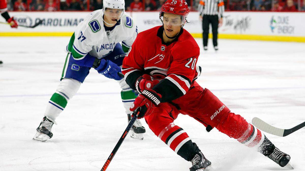 Carolina Hurricanes’ Sebastian Aho (20) gathers in the puck in front of Vancouver Canucks’ Nikolay Goldobin (77) during the second period.