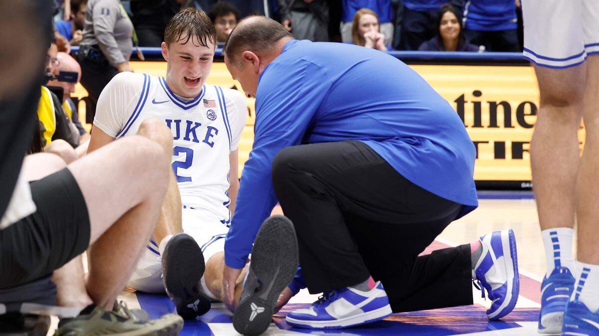 Duke head men’s basketball trainer Jose Fonseca examines Cooper Flagg (2) after he didn’t get up after chasing a ball during the second half of Duke’s 96-62 victory over Maine at Cameron Indoor Stadium in Durham, N.C., Monday, Nov. 4, 2024.