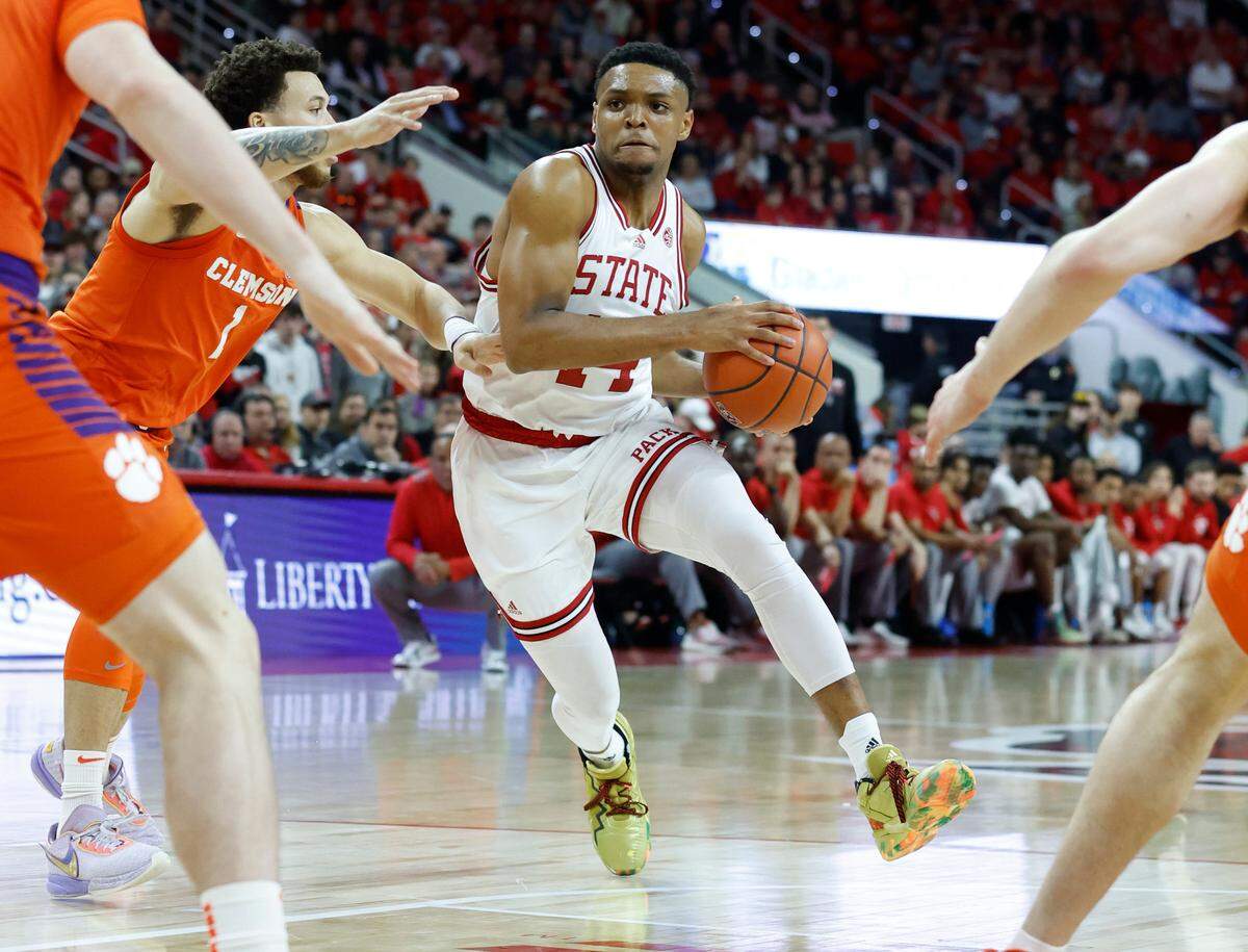 N.C. State’s Casey Morsell (14) drives by Clemson’s Chase Hunter (1) during the first half of N.C. State’s game against Clemson at PNC Arena in Raleigh, N.C., Saturday, Feb. 25, 2023.