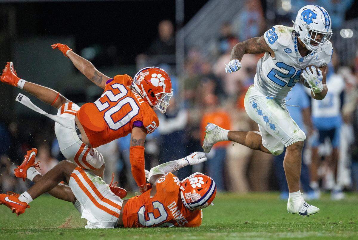 North Carolina’s Omarion Hampton (28) breaks open and hurdles away from Clemson’s Avieon Terrell (20) and Kahlil Barnes (36) on a 55-yard touchdown run in the third quarter on Saturday, November 18, 2023 at Memorial Stadium in Clemson, S.C. Hampton rushed for 178 yards and two touchdown in the Tar Heels’ 31-20 loss.