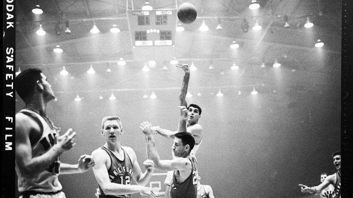 Lennie Rosenbluth shoots over Wake Forest defenders in the 1957 ACC Tournament. A haze of cigarette and cigar smoke hangs in the air as was often the case in Reynolds before smoking was banned from the arena decads later.