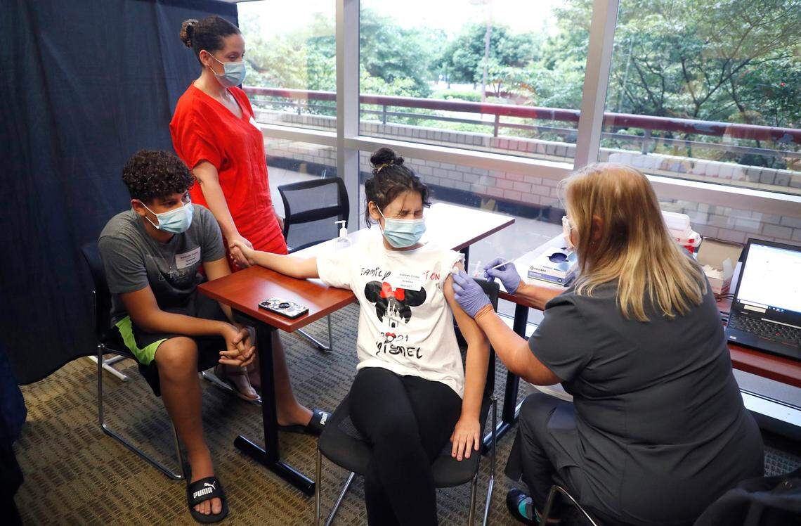 Ismelda Rosario holds her daughter’s hand, Yismel Gonzalez, 12, as she get her COVID-19 vaccine from Pam Scott, RN, during the WakeMed Back-to-School Blitz vaccine clinic at the WakeMed Raleigh Campus in Raleigh, N.C., Sunday, August 1, 2021. Yismel’s brother, Franklin Gonzalez, 13, left, watches.
