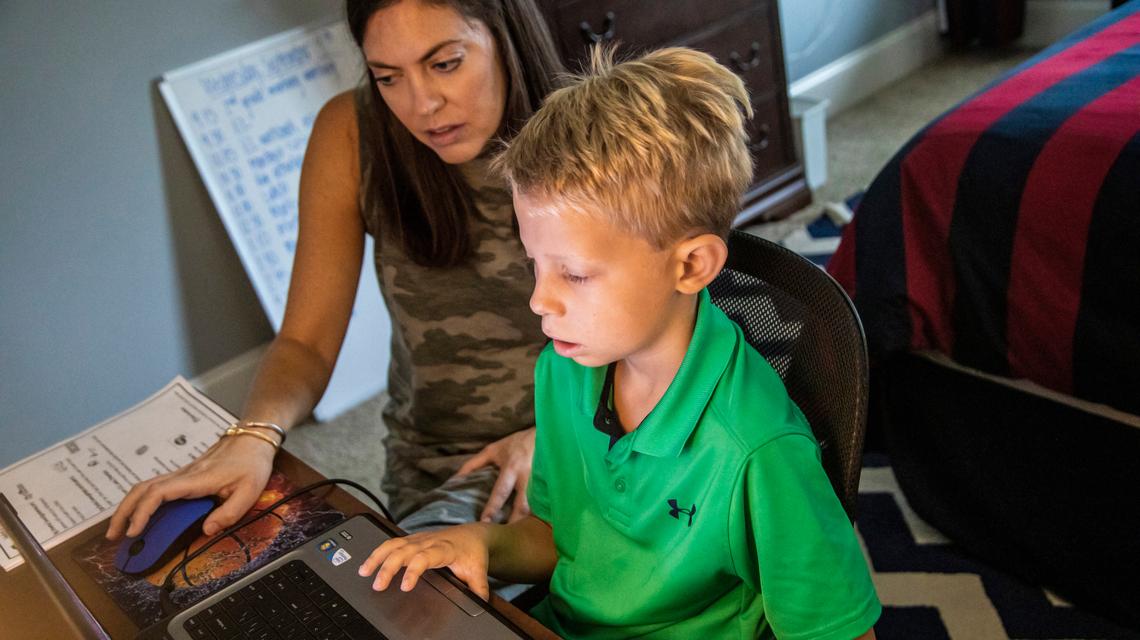 Erin Wall helps her son Carter, a second-grader Penny Road Elementary, prepare for a remote learning lesson Wednesday, Sept. 9, 2020 at their home in Cary.