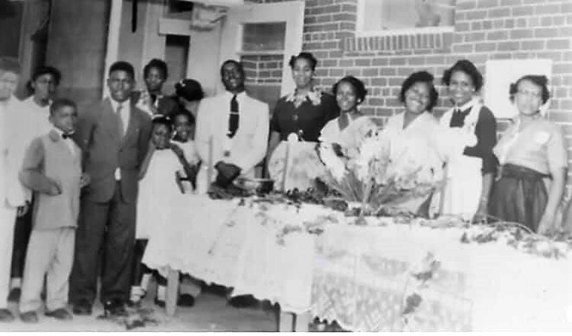 Students, cafeteria staff and teachers gather together around a table at the all-Black Holly Springs Elementary School in this undated photo.