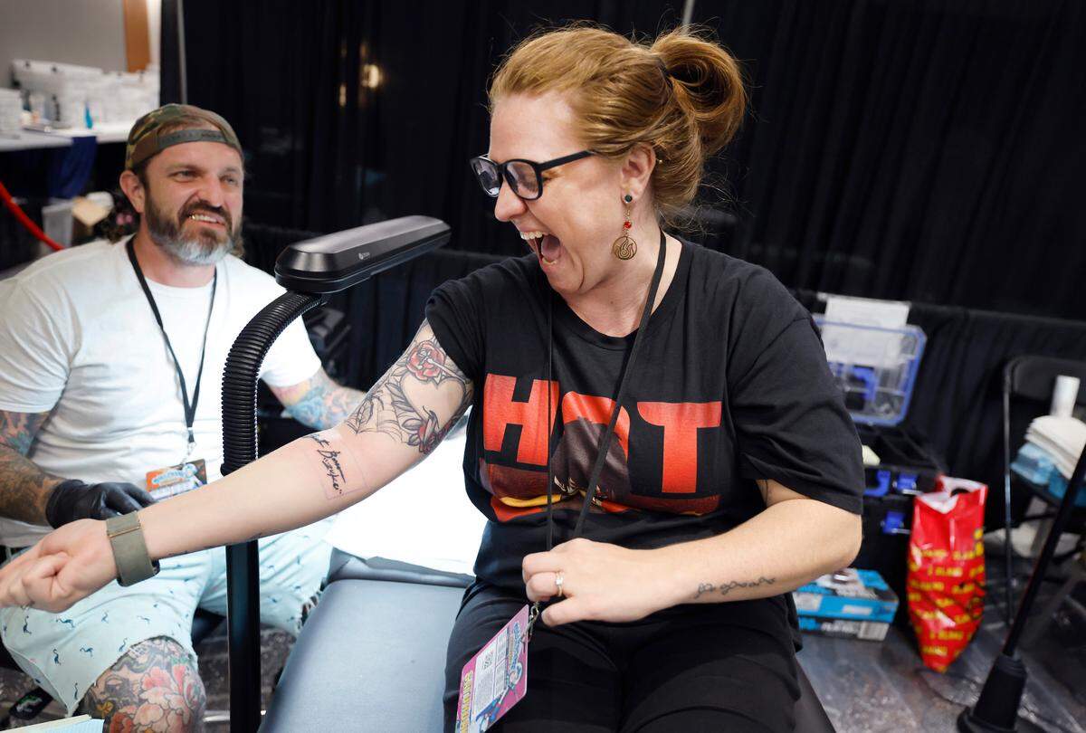 Danielle Christensen of Wendell gets her first look at the tattoo of Dante Bosco on her arm at GalaxyCon in Raleigh, N.C., Saturday, July 27, 2024. The tattoo is part of GalaxyCon’s celebrity tattoo experience where you get a body part autographed by talent and then right afterward get the signature tattooed by River City Tattoo Company. Christensen’s tattoo artist Adam Phillips is to the left.