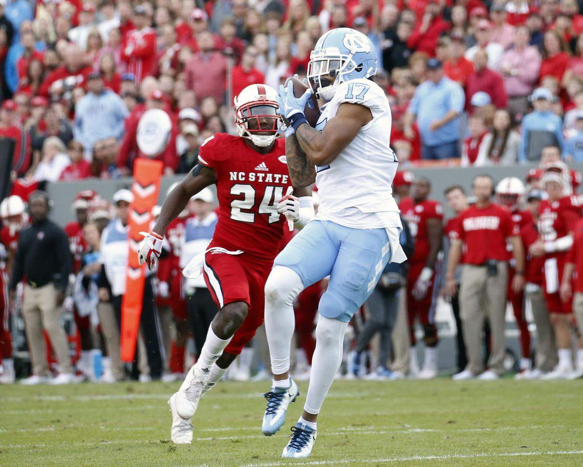 UNC’s JAnthony Ratliff-Williams (17) hauls in a pass for a TD in front of N.C. State’s Nakia Robinson Jr. (24) during the first quarter of an ACC college football game between the N.C. State Wolfpack and the UNC Tar Heels played at Carter-Finley Stadium in Raleigh, NC, on Nov. 25, 2017.  