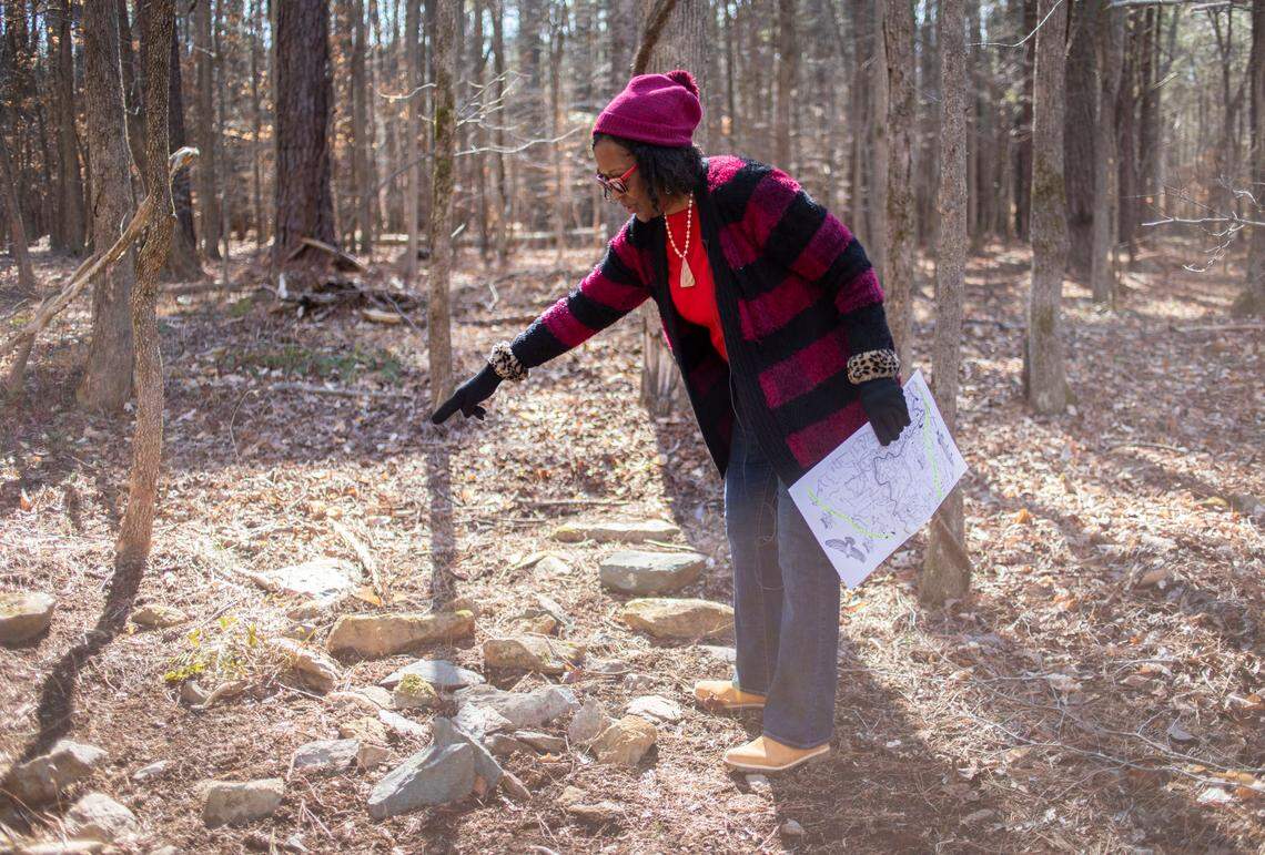 Retired Judge Beverly Scarlett points out some of the Indigenous burial rocks arranged in the woods near her home in Hillsborough, N.C. on Wednesday, Feb. 15, 2022.