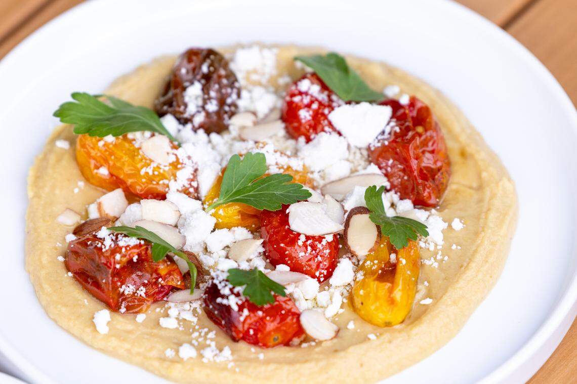 Toor Whip featuring blistered cherry tomatoes, lemony lentil puree, ricotta salata, and almonds during a soft opening Thursday June 15, 2023 at Ajja, a new restaurant from Cheetie Kumar and Paul Siler in on Bickett Blvd. in Raleigh. Ajja focuses on Mediterranean, Middle Eastern and Southwest Asian flavors.