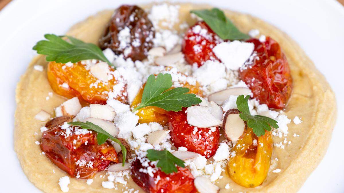 Toor Whip featuring blistered cherry tomatoes, lemony lentil puree, ricotta salata, and almonds during a soft opening Thursday June 15, 2023 at Ajja, a new restaurant from Cheetie Kumar and Paul Siler in on Bickett Blvd. in Raleigh. Ajja focuses on Mediterranean, Middle Eastern and Southwest Asian flavors.