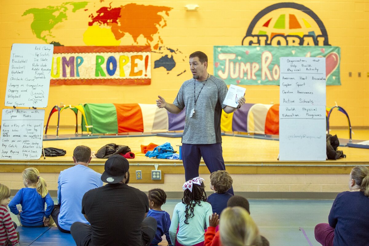 Quinn McLaney, physical education teacher at Timber Drive Elementary, talks to students and parents gathered for a class during ‘Bring Your Parent To PE Week’, his idea to involve parents in exercising with their kids at home, on Thursday, Nov. 29, 2018, in Garner, NC.
