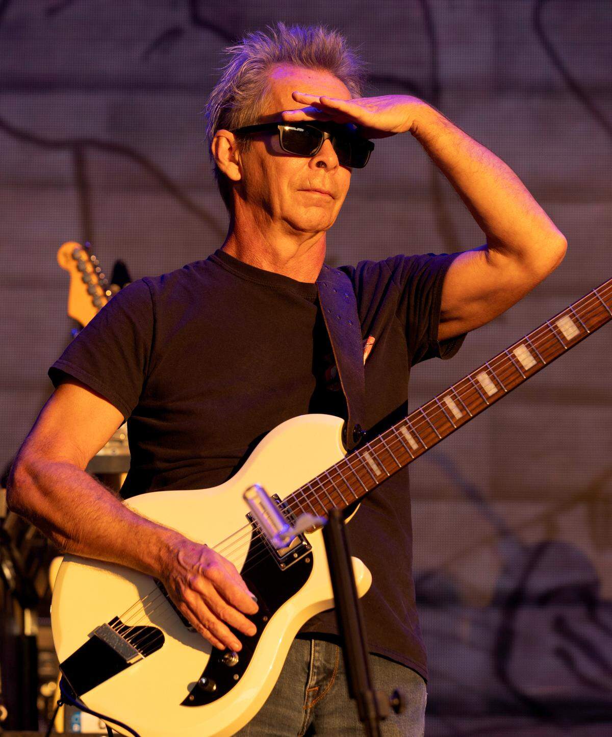 Guitar player Tim Reynolds shades his eyes from the bright setting sun as he surveys the crowd after The Dave Matthews Band took the stage at Raleigh, N.C.’s Coastal Credit Union at Walnut Creek, Friday night, June 14, 2024.