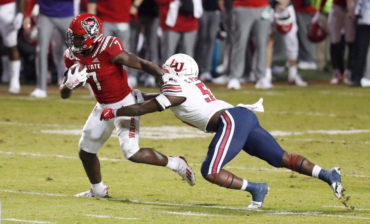 N.C. State running back Zonovan ‘Bam’ Knight (7) avoids the tackle by Liberty linebacker Carl Poole (57) during the first half of N.C. State’s game against Liberty at Carter-Finley Stadium in Raleigh, N.C., Saturday, Nov. 21, 2020.