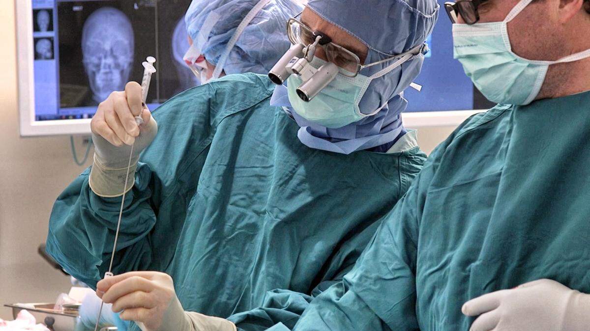 Dr. Allan Friedman places a catheter into a tumor in a patient's brain during a procedure at Duke Hospital. The catheter delivers a genetically modified form of the poliovirus to treat glioblastoma.