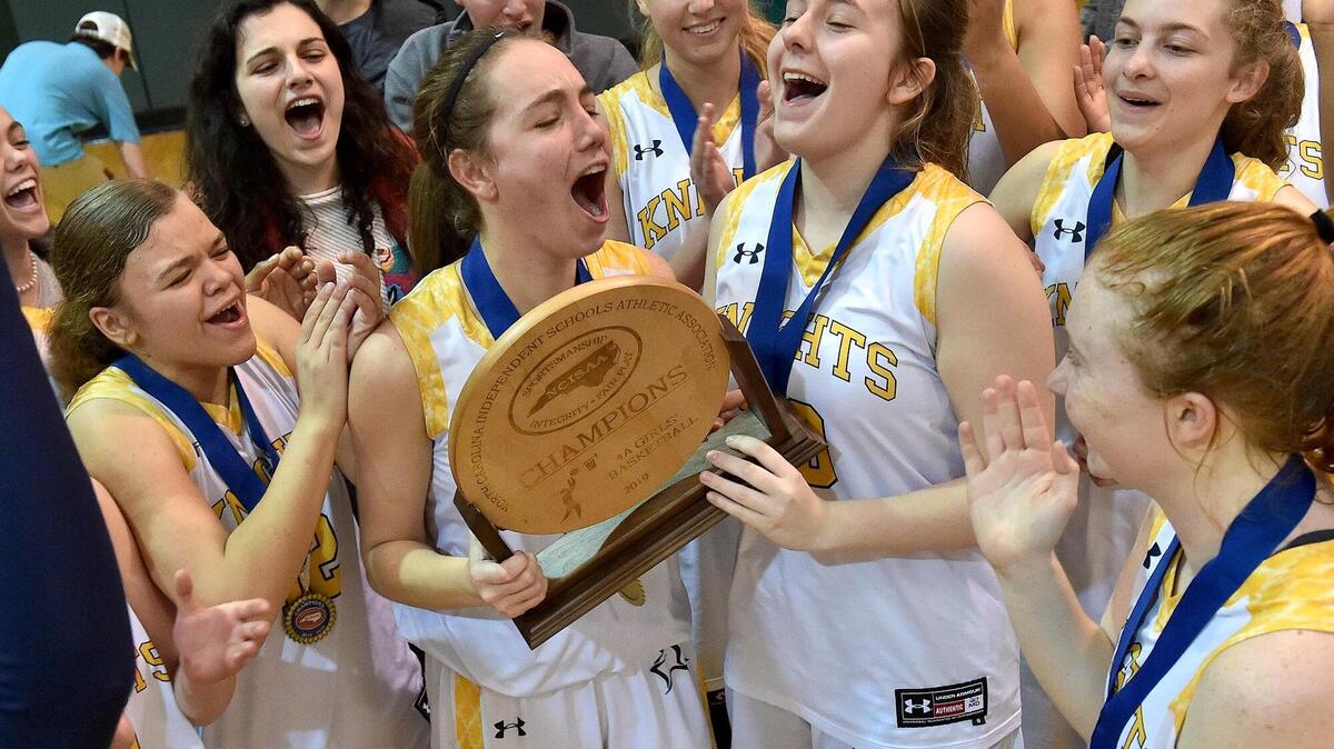 North Raleigh Christian’s Emma Finster (5) and Emily Pennington (20), along with teammates, celebrate with the NCISAA 4A trophy after their win over Ravenscroft. The Ravenscroft Ravens and the North Raleigh Christian Knights met in the NCISAA 4A basketball championships in Raleigh, N.C. on February 23, 2019.