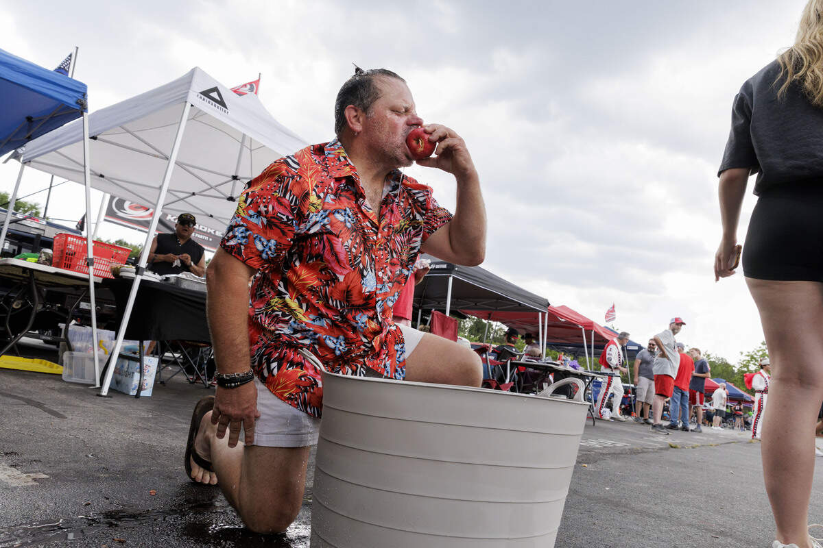 Dougie Welch takes a bite from an apple he scored while apple bobbing in the parking lot outside the Lenovo Center on June 11, 2026, in Raleigh, North Carolina. The Carolina Hurricanes take on the Vegas Golden Knights for Game 5 of the Stanley Cup Final.
