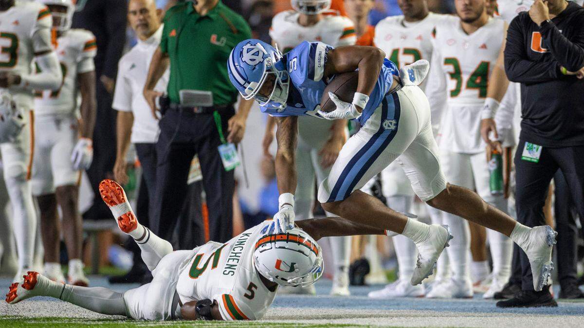 North Carolina’s J.J. Jones (5) picks up 48 yards on a pass completion from quarterback Drake Maye before being stopped by Miami’s Kamren Kinchens (5) in the first quarter on Saturday, October 14, 2023 at Kenan Stadium in Chapel Hill, N.C.