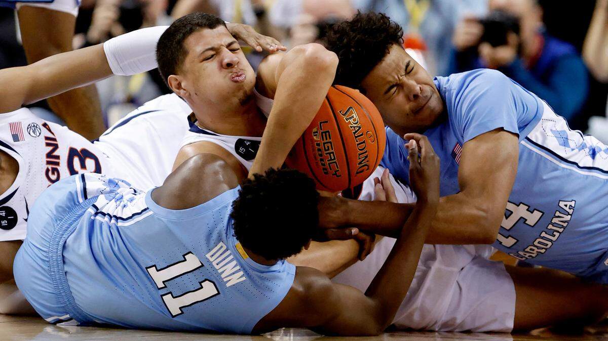 North Carolina’s D’Marco Dunn (11) and Puff Johnson (14) fight for the loose ball with Virginia’s Kadin Shedrick (21) during the first half of UNC’s game against Virginia in the quarterfinals of the ACC Men’s Basketball Tournament in Greensboro, N.C., Thursday, March 9, 2023.