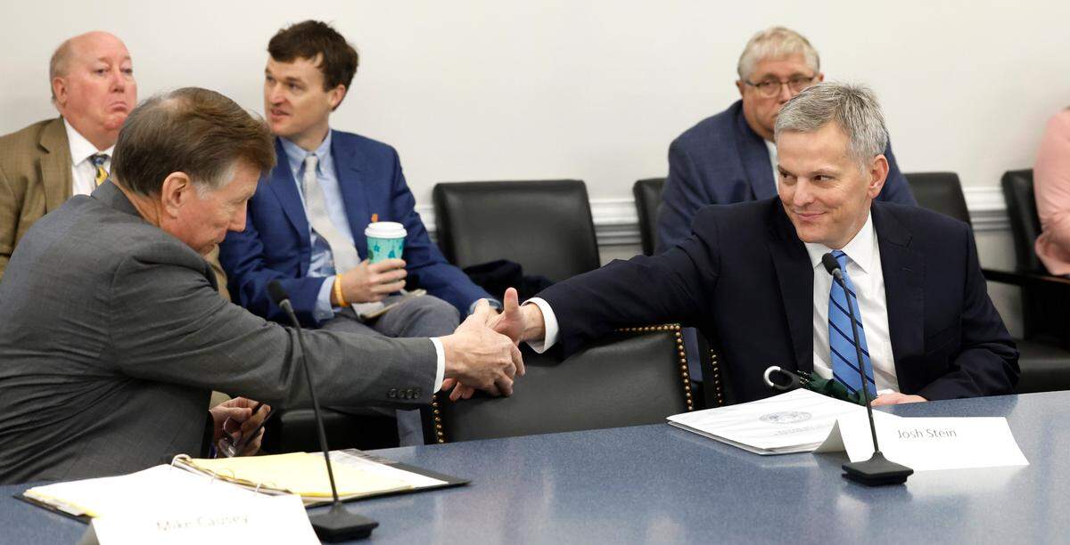 North Carolina Attorney General Josh Stein, right, greets Commissioner of Insurance Mike Causey before the Council of State meeting in Raleigh, N.C., Tuesday, Jan. 9, 2024.