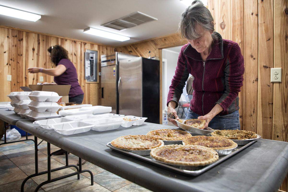 Debbie Wells, right, places pieces of quiche into styrofoam containers for residents with Melinda Sutton, left, at the Ocracoke Community Center on Saturday, Nov. 23, 2019.