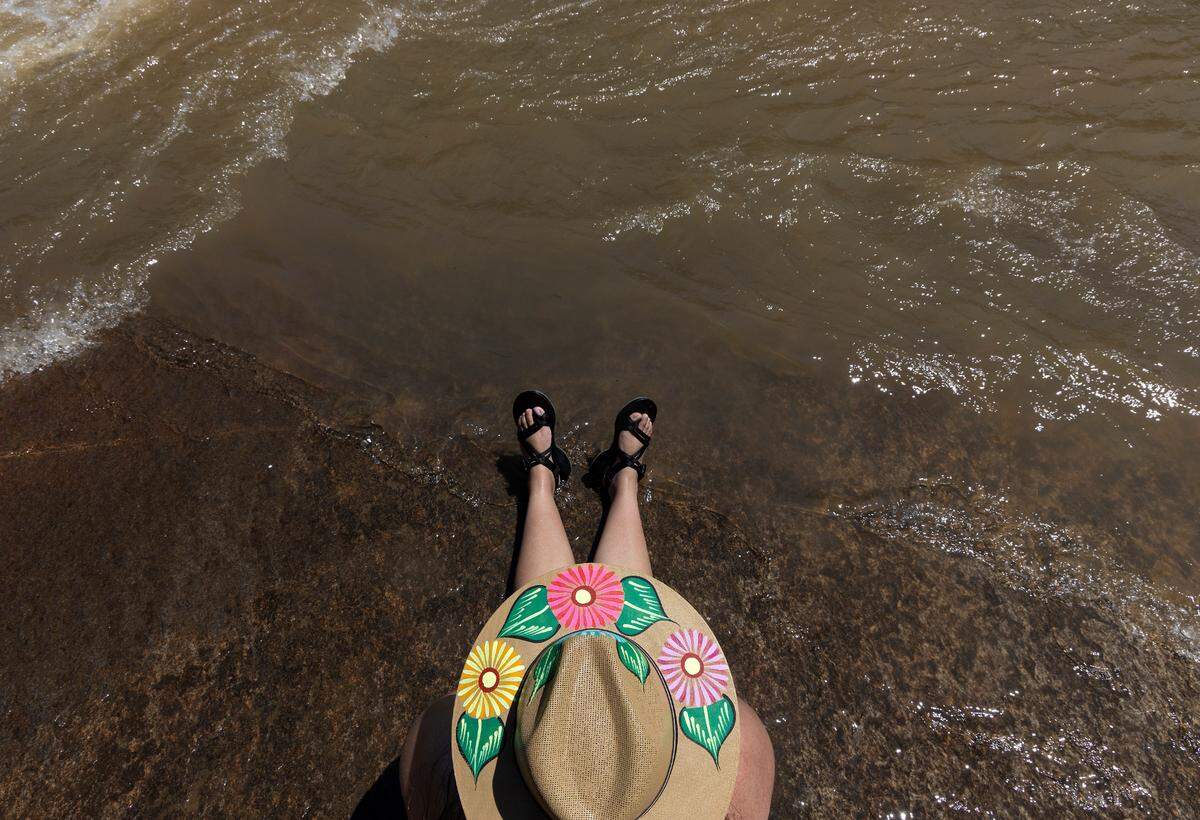 Mitzy Martin of Asheville, N.C., sits at the water’s edge at RiverPark at Cooleemee Falls on Saturday, Aug. 5, 2023, in Woodleaf, N.C.