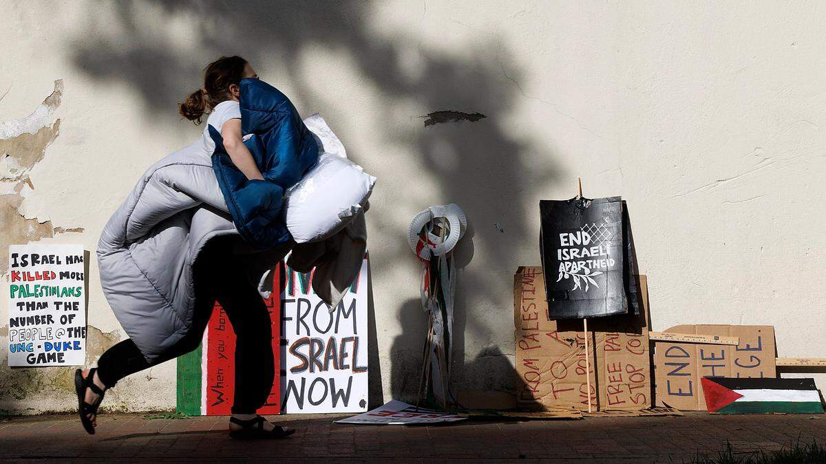A person walks by signs outside of the Campus Y building hours after UNC-Chapel Hill police detained members of a pro-Palestinian “Gaza solidarity encampment” early Tuesday morning.