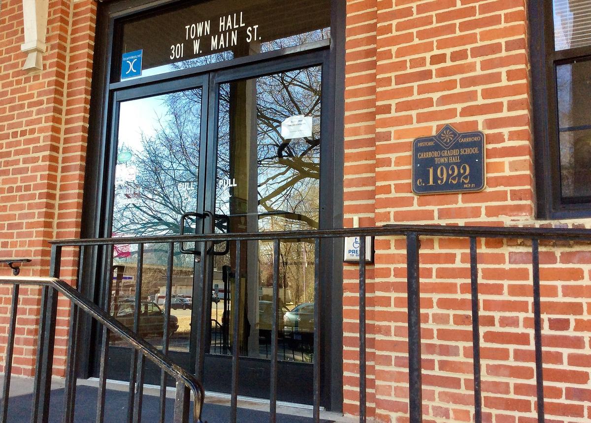 A Truth Plaque planned for the left side of Carrboro Town Hall’s front door would be similar to one already posted there. The existing plaque marks the Town Hall building as the site of Carrboro’s Graded School, established in 1922.