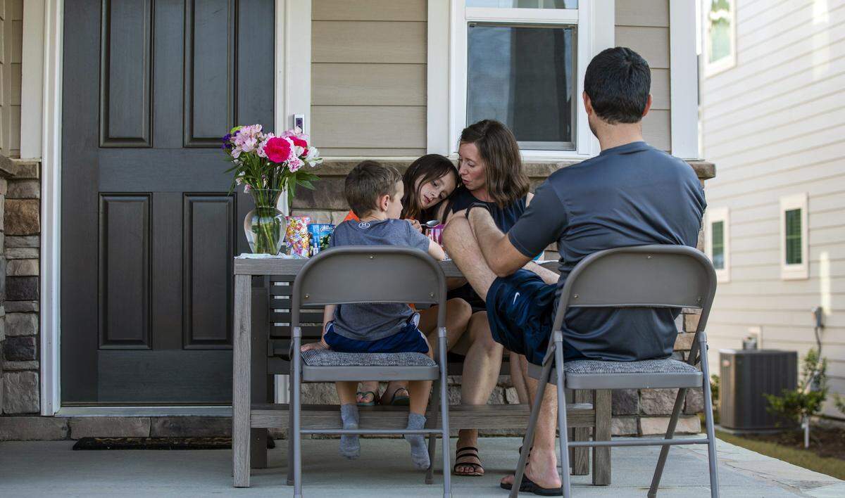 From left, Dylan, Deanna, Jen, and Darren Drake eat dinner together on their front porch in hopes of bringing more neighbors out of their homes to connect at a safe social distance during dinner time, on Friday, Mar. 27, 2020, in Holly Springs, N.C.
