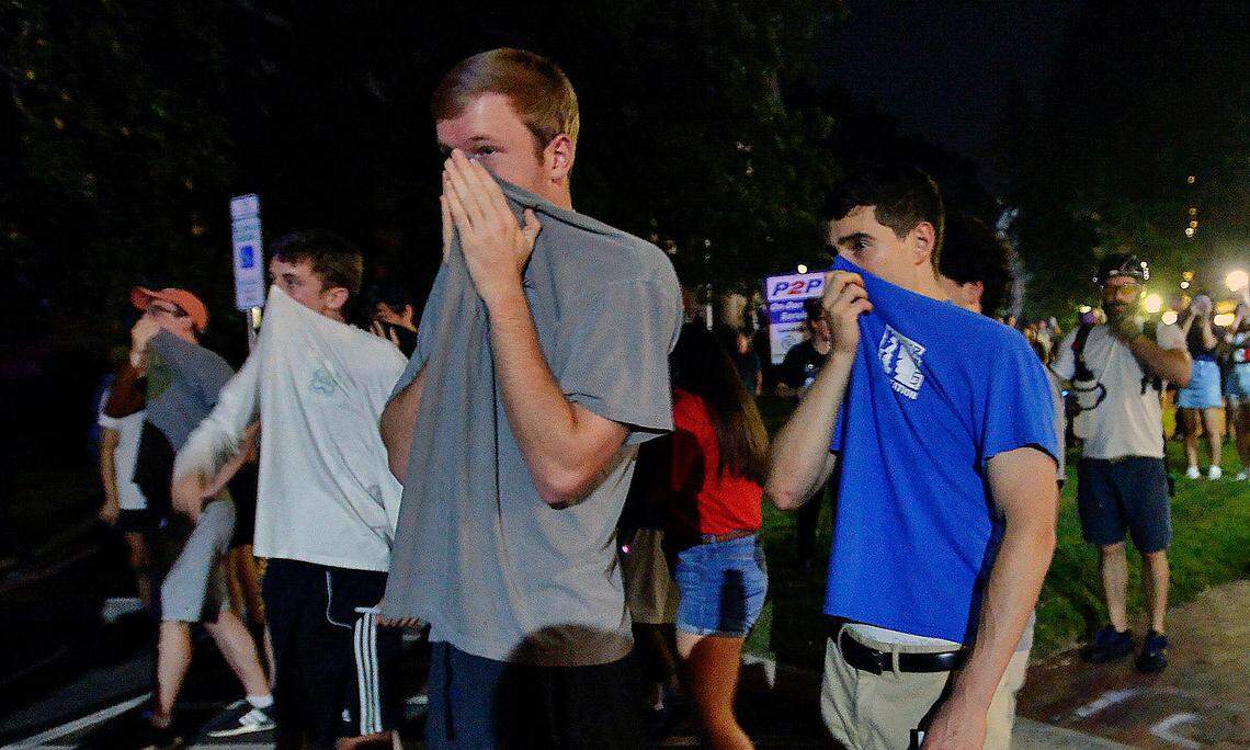 Protesters cover their faces after pepper spray is deployed behind Graham Memorial Hall on the campus of UNC-Chapel Hill, Thursday, August 30, 2018 during a rally to commemorate the Confederate statue known as Silent Sam.