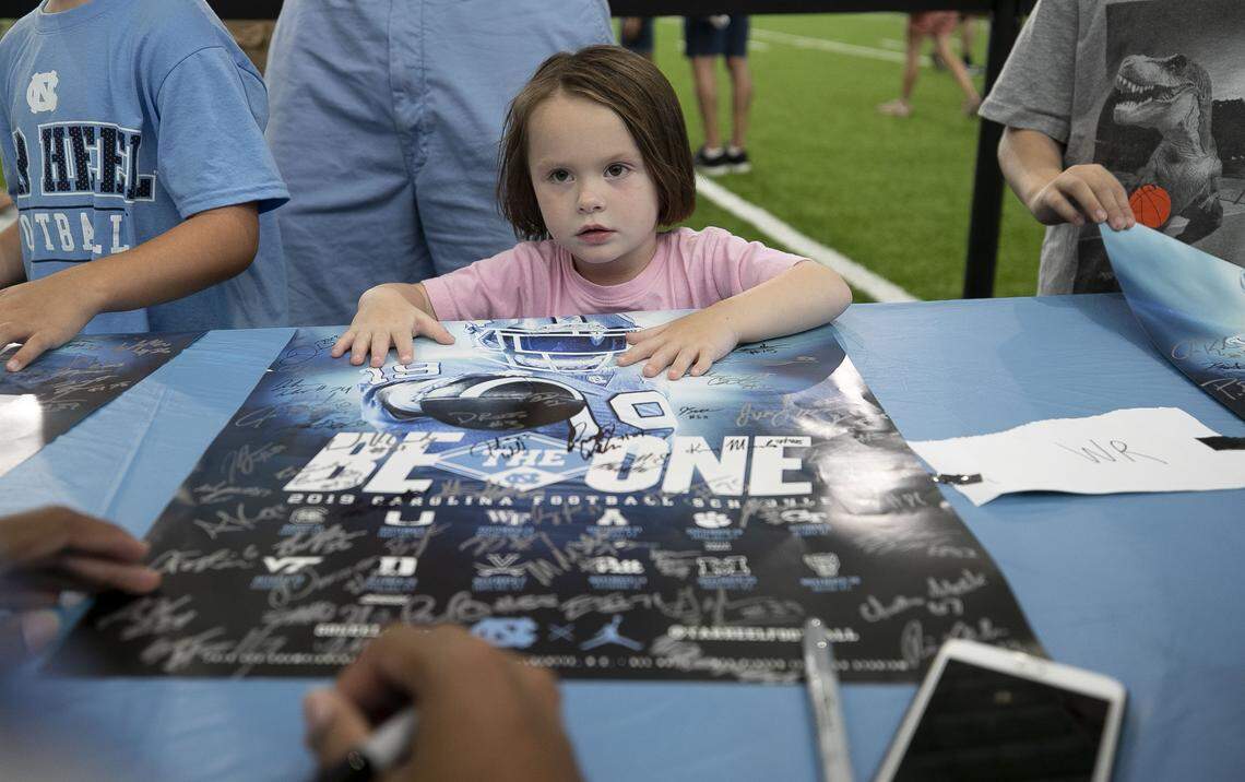 Three-year-old Shea Caudill of Mebane, N.C. gets an autograph from North Carolina receiver Welton Spottsville (17) during the annual Meet The Heels event on Saturday, August 3, 2019 at the Football Practice Complex in Chapel Hill, N.C.