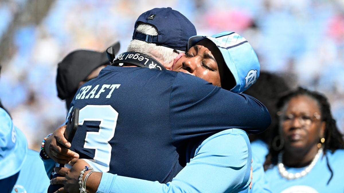 North Carolina Tar Heels head coach Mack Brown and September Craft hug during an Oct. 12 tribute to former player Tylee Craft, who died of lung cancer.