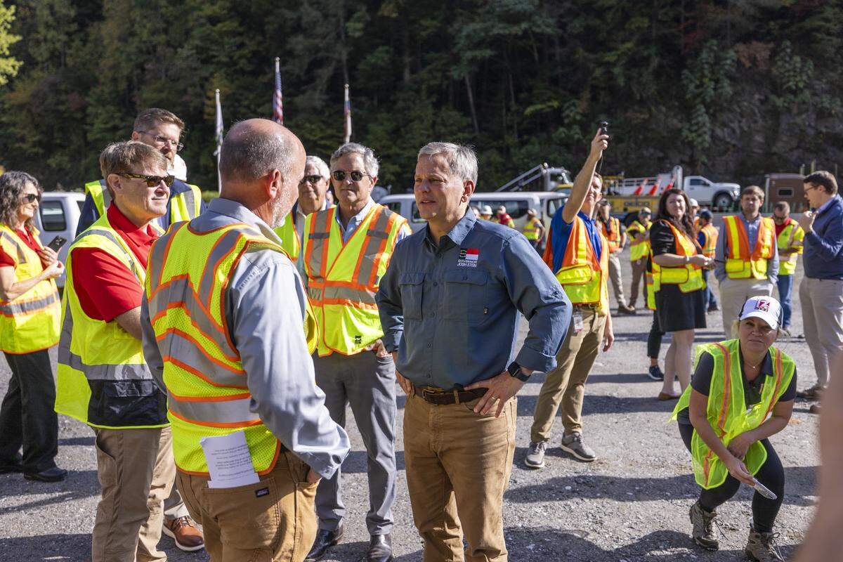Gov. Josh Stein, center, speaks with Federal Highway Administrator Sean McMaster, left, before a news conference Friday, Sept. 26, 2025, in a roadwork staging area on Interstate 40 in Pigeon River Gorge. The event marked one year since Hurricane Helene caused catastrophic damage to the highway near the North Carolina-Tennessee state line.
