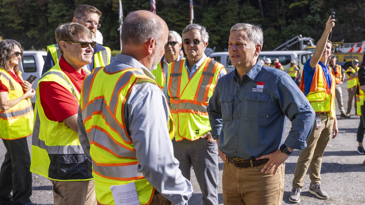 Gov. Josh Stein, center, speaks with Federal Highway Administrator Sean McMaster, left, before a news conference Friday, Sept. 26, 2025, in a roadwork staging area on Interstate 40 in Pigeon River Gorge. The event marked one year since Hurricane Helene caused catastrophic damage to the highway near the North Carolina-Tennessee state line.