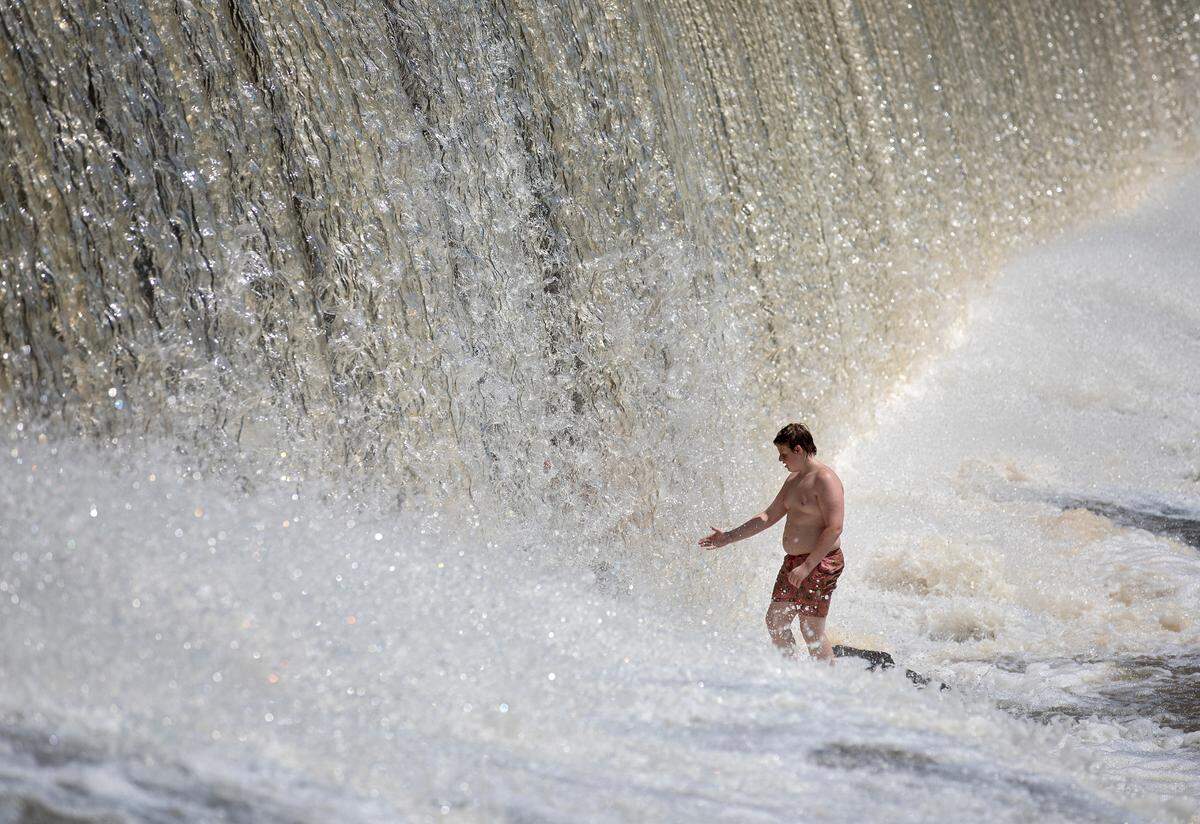 Maddux Crowe, 12, reaches out a hand through a waterfall at RiverPark at Cooleemee Falls on Saturday, Aug. 5, 2023, in Woodleaf, N.C.