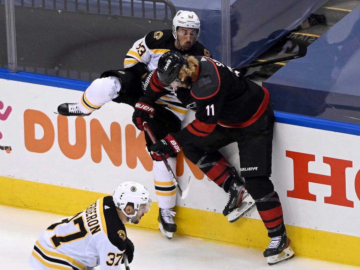 Boston Bruins left wing Brad Marchand (63) checks Carolina Hurricanes center Jordan Staal (11) during first-period NHL Eastern Conference Stanley Cup playoff hockey action in Toronto, Monday, Aug. 17, 2020. (Nathan Denette/The Canadian Press via AP)