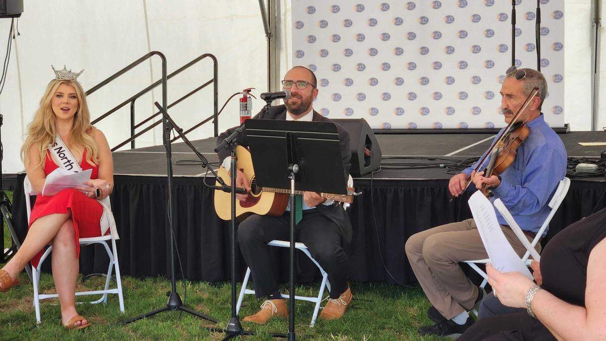 N.C. Rep. Caleb Rudow, center, an Asheville Democrat, leads a bipartisan sing-a-long on Halifax Mall outside the Legislative Building in downtown Raleigh, on Wednesday, May 22, 2024. On the left are 2023 Miss North Carolina Taylor Loyd and on the right is Rudow’s father, Marc Rudow, on fiddle.
