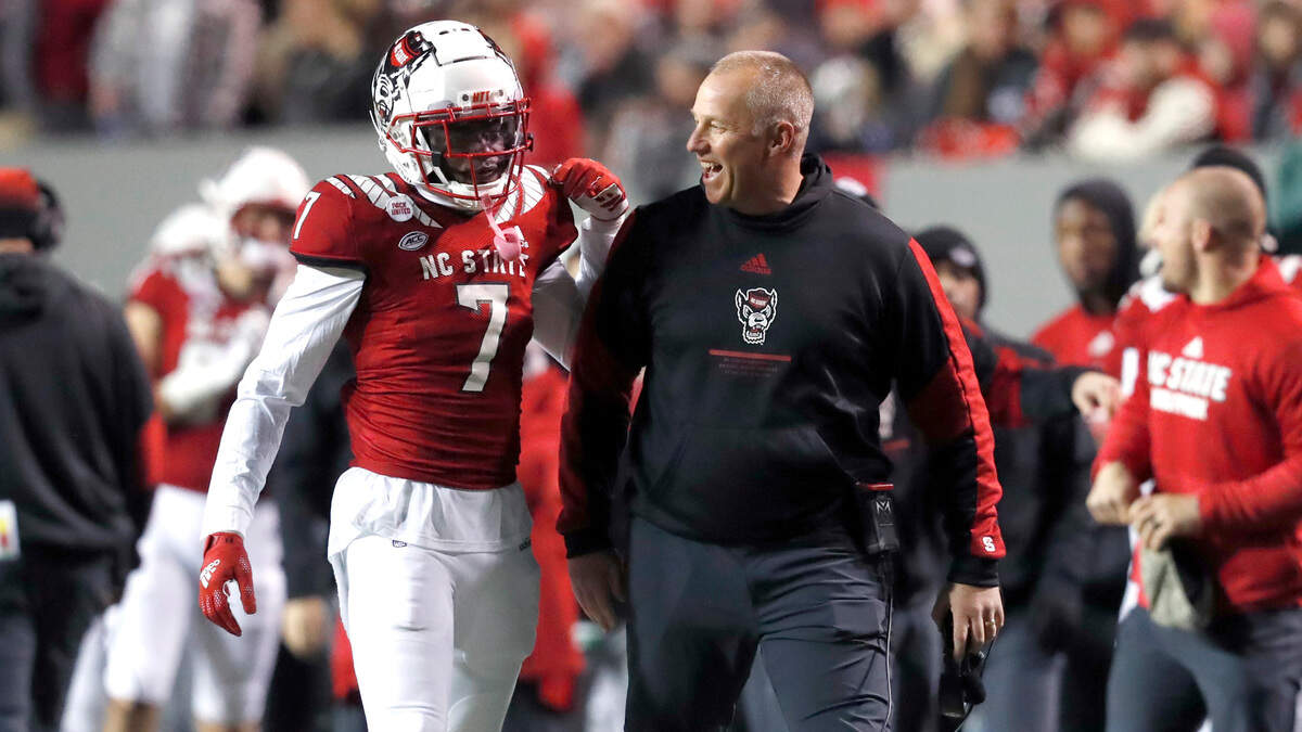 N.C. State head coach Dave Doeren laughs with Chris Ingram (7) during the first half of N.C. State’s game against UNC at Carter-Finley Stadium in Raleigh, N.C., Friday, November 26, 2021.