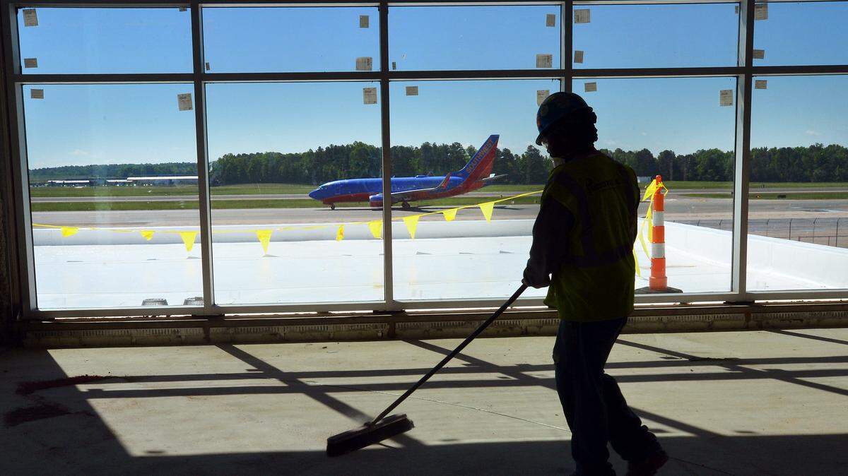 A worker sweeps up in Terminal 1 as a Southwest Airlines plane lands in this file photo from May 2013. RDU plans to reopen four dormant gates in the terminal because of passenger growth.