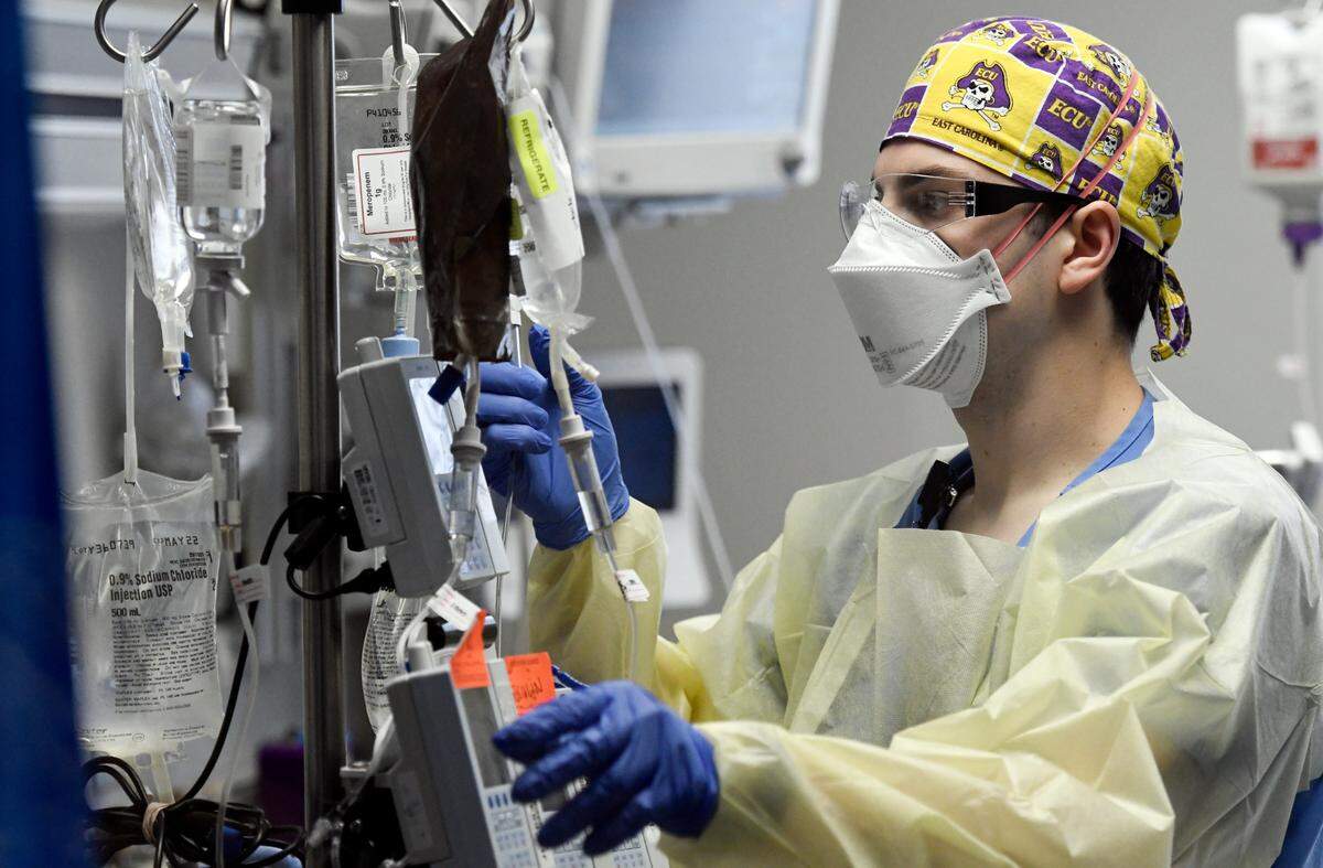 Jonathan Vitek, a registered nurse at UNC Rex Hospital, checks numerous IV medications and fluids being administered to a COVID patient in the spring of 2021.