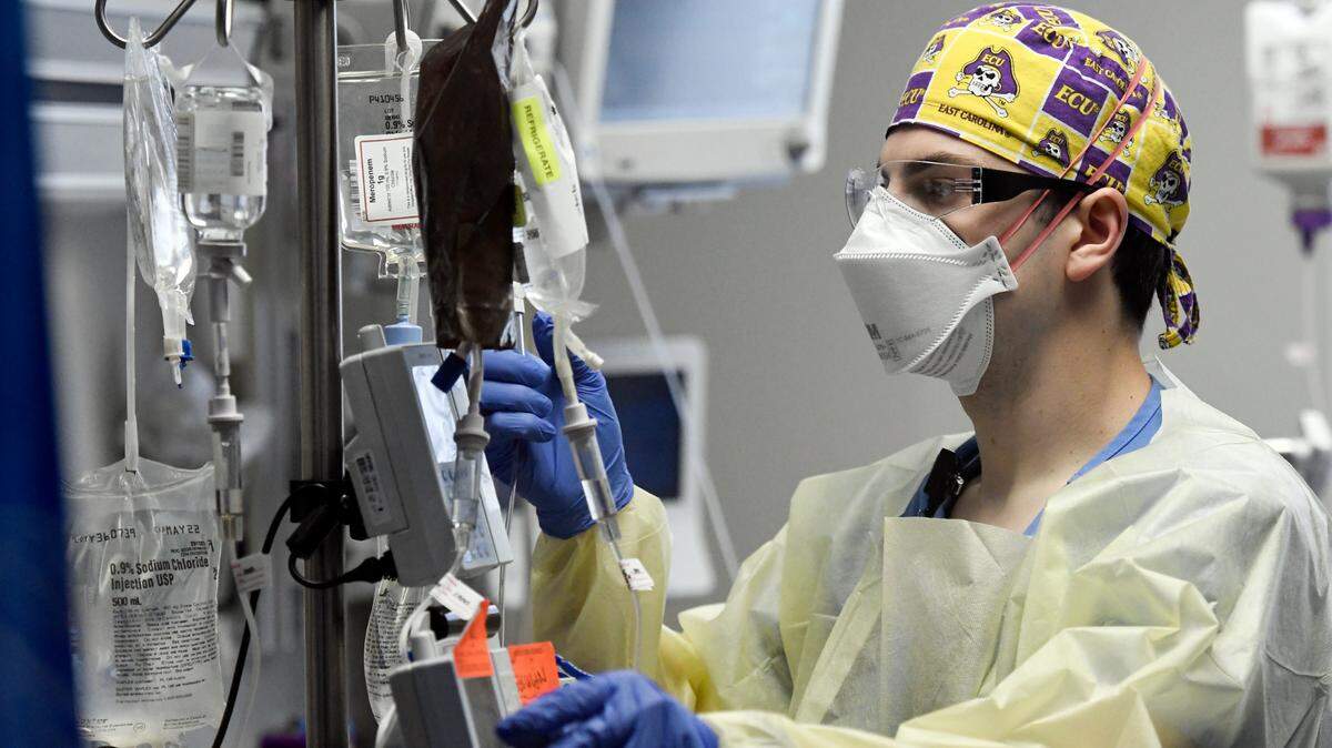 Jonathan Vitek, RN, checks numerous IV medications and fluids being administered to a COVID patient. The explosion of COVID-19 patients has helped fill beds and emergency rooms at Duke Raleigh, UNC Rex and WakeMed hospitals in Wake County.