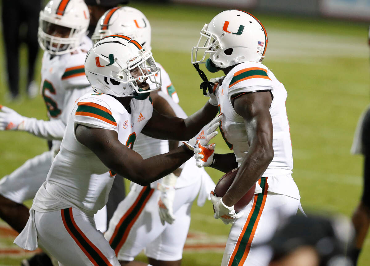 Miami linebacker Gilbert Frierson (3), left, celebrates with cornerback DJ Ivey (8) after Ivey intercepted the ball late in the second half of Miami’s 44-41 victory over N.C. State at Carter-Finley Stadium in Raleigh, N.C., Friday, Nov. 6, 2020.