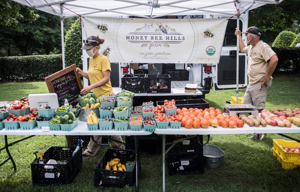 Liz and Rich Mason, owners of Honey Bee Hills Farm in Prospect, Hill, N.C. set up their tent at the Fearrington Village Farmer’s Market in Fearrington, N.C. on Tuesday, Aug. 18, 2020.