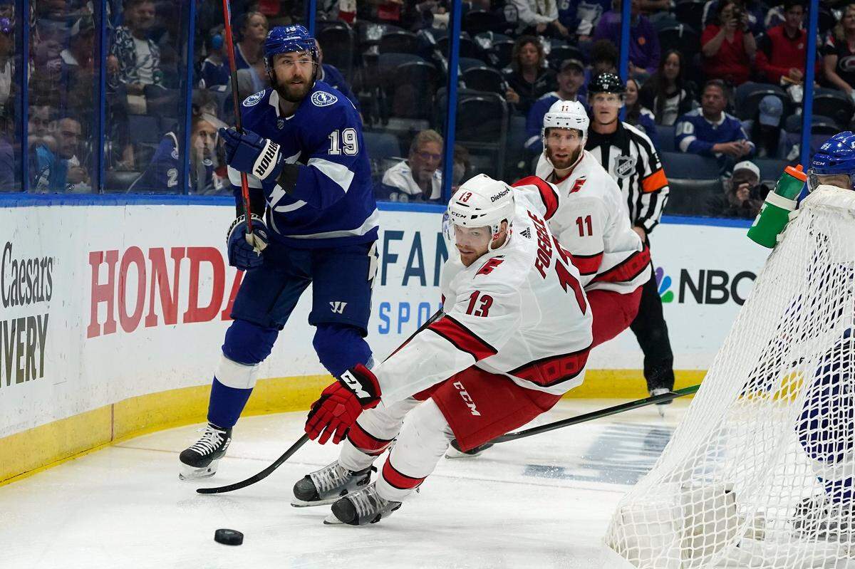 Carolina Hurricanes left wing Warren Foegele (13) intercepts a pass by Tampa Bay Lightning right wing Barclay Goodrow (19) during the first period in Game 3 of an NHL hockey Stanley Cup second-round playoff series Thursday, June 3, 2021, in Tampa.