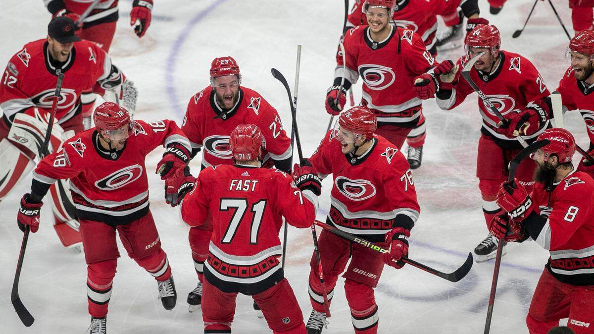 The Carolina Hurricanes swarm to Jesper Fast (71) during their post-game celebration after Fast scored the game winning goal in overtime to secure a 3-2 victory over the New Jersey Devils, clinching their second round Stanley Cup series on Thursday, May 11, 2023 at PNC Arena in Raleigh, N.C.