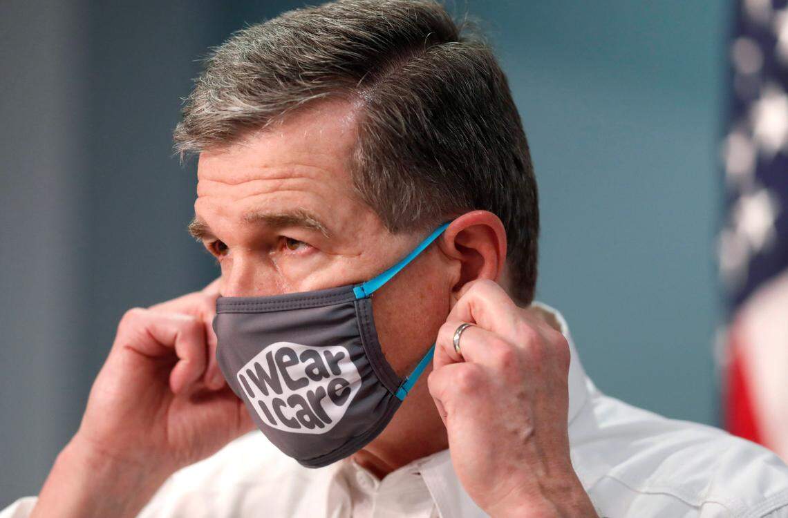 Gov. Roy Cooper prepares to take off his mask to talk during a briefing at the Emergency Operations Center in Raleigh, N.C., Wednesday, August 5, 2020.