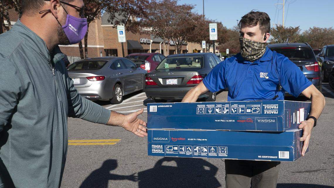 Best Buy employee Kane Foreman helps customer Kevin Tackett load the three televisions he purchased into his vehicle at Crossroads plaza on Friday, November 20, 2020 in Cary, N.C.