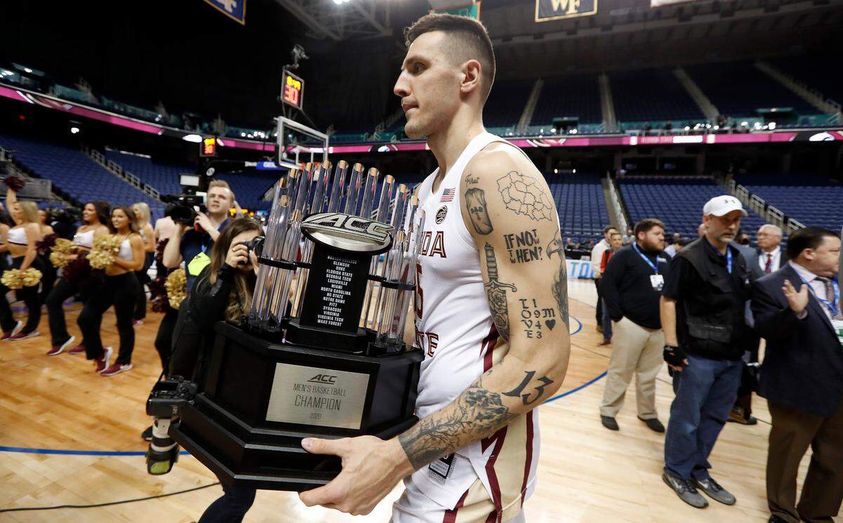 Florida State’s Dominik Olejniczak walks off the floor with the ACC championship trophy at the Greensboro Coliseum Thursday, March 12, 2020, after it was announced the ACC basketball tournament had been canceled amid rapidly increasing concerns about the spread of COVID-19, the coronavirus disease.