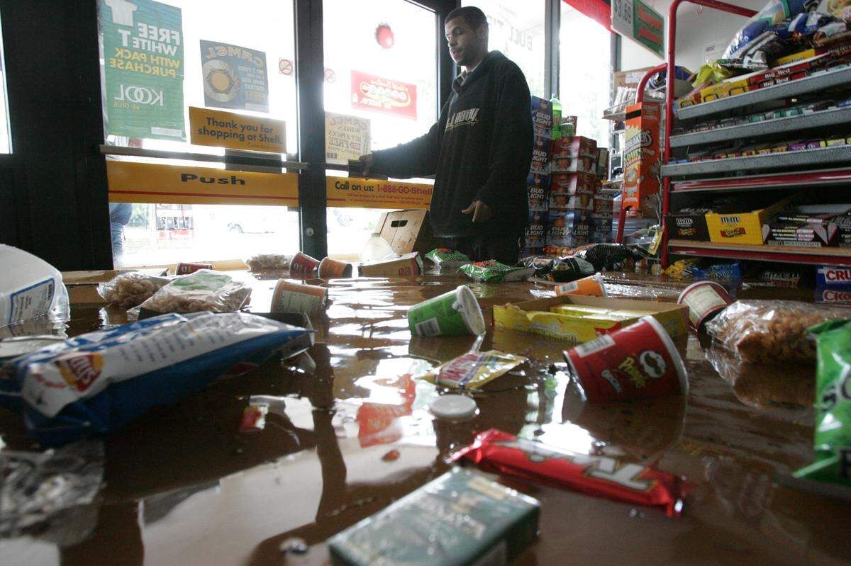 Humza Quyyum, an employee at the Crabtree Shell, surveys the damage of the store near Crabtree Valley Mall after it was flooded in 2006 as the remnants of tropical storm Alberto moved over the Triangle.